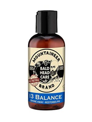 Bald head care spray bottle on wooden table with fresh herbs and apple cider vinegar