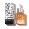 A sleek glass bottle of Bare, Thriving Rejuvenate Face Oil, surrounded by fresh botanical elements, emphasizing its natural and vegan formula